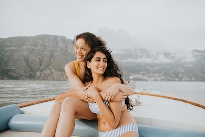 two women smile and hug on a boat ride as they consider how the july 2023 super buck moon will affec...