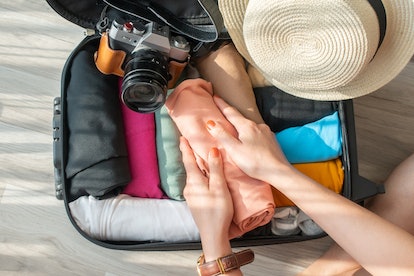 A woman rolls her clothes to better fit them into a carry-on bag before a trip.