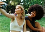 two friends pose for a selfie during a picnic as they think about how their zodiac signs will be the...