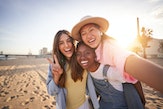 three women pose for a selfie at the beach as they consider why the July 2023 super buck moon will a...