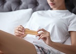 Young woman with birth control pills in bedroom. Gynecology