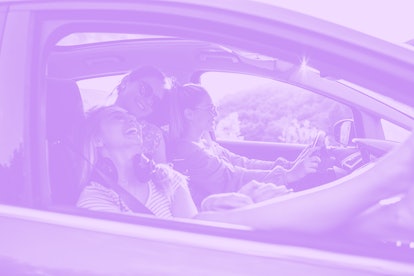 Three female friends driving in a car on a post-graduation trip 