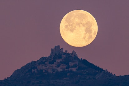 A large full moon is seen rising over a city on a hill. In astrology, an aquarius moon can boosts co...