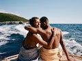 Portrait of smiling woman arm around with boyfriend on boat deck against sky during sunny day
